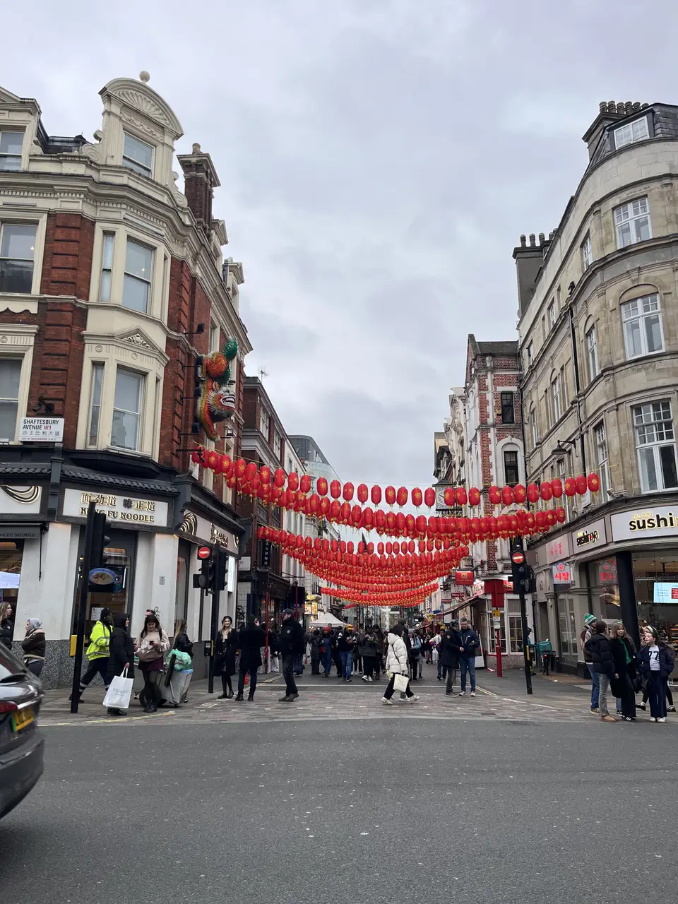 Rows of red lanterns strung above a busy Chinatown street lined with restaurants